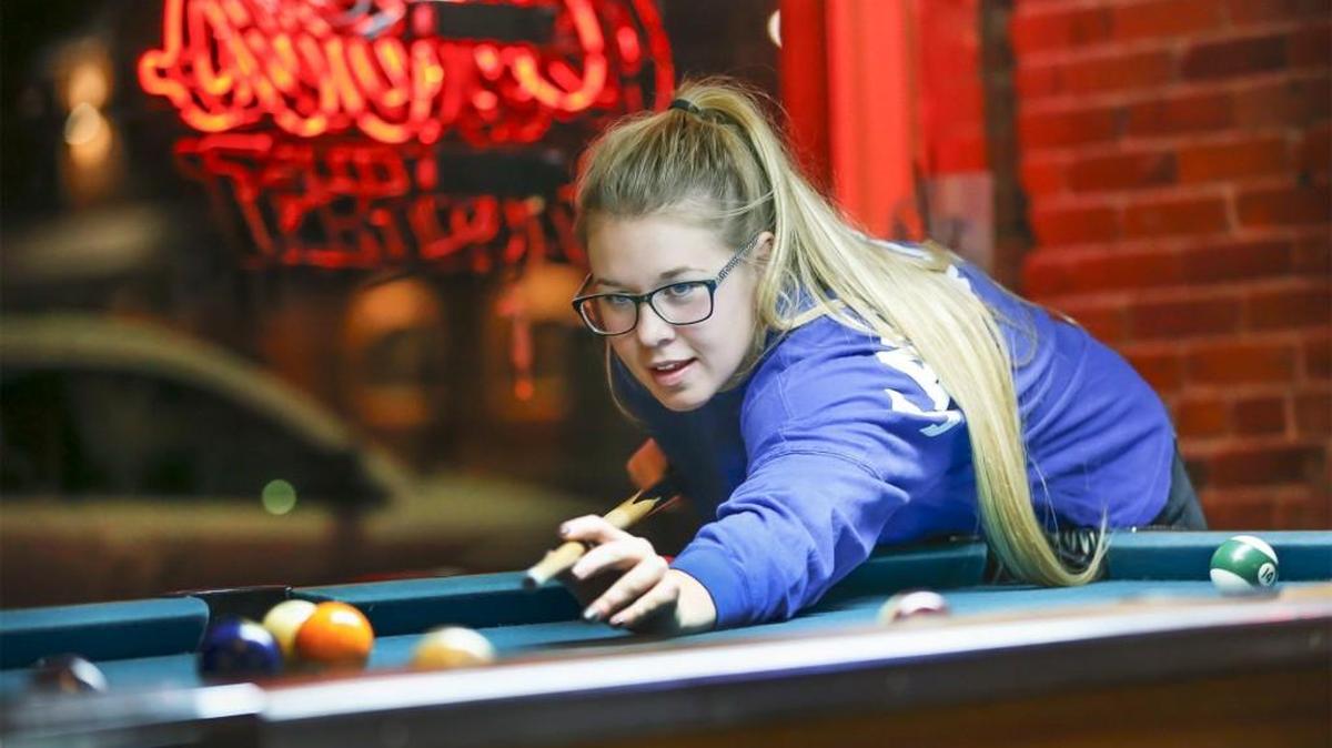 Taylor Mannis, 20, plays pool at Emerson Biggin’s in December. Biggin’s is one of the few places that allows an under-21 crowd to hang out until 10 p.m.