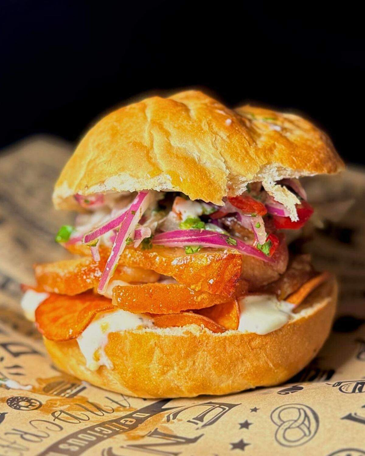 The Peruvian Pork Legend at Lima Kitchen features crispy pork belly topped with sweet potato chips, house-made mayonnaise and Peruvian salsa on a house-made bun.