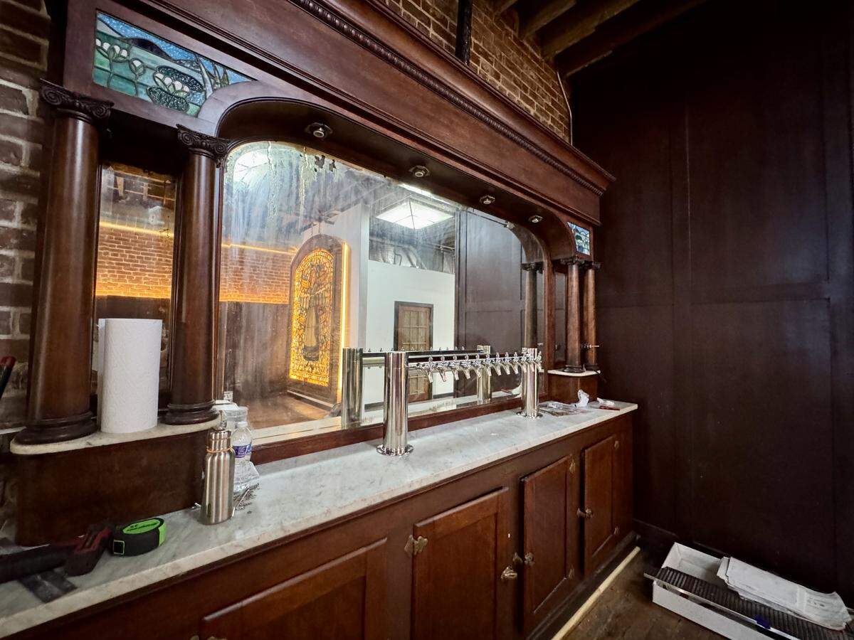 A stained-glass “beer angel” that will decorate the main floor of Prost’s new space is reflected in the mirror of its antique bar.
