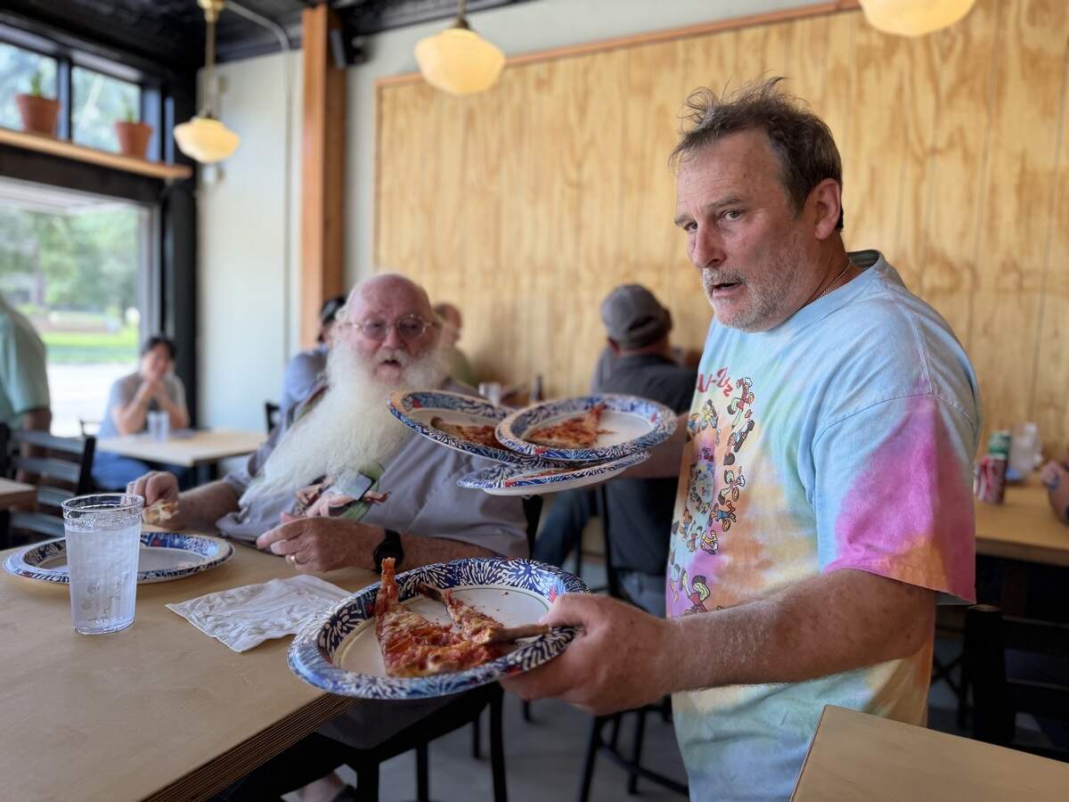 Tom Geagan, right, delivers slices of New Haven-style pizzas as part of a test run for his new restaurant, Tommy’s Apizza. He invited many of the construction workers and electricians who helped put his restaurant together.