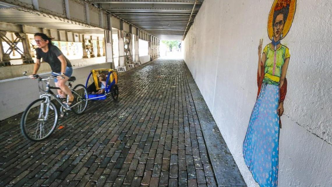 A cyclist makes her way down Douglas under the bridge near Union Station on Tuesday. The city just recently power-washed the sidewalks for a Final Friday art show that will be there this weekend. (June 27, 2017)