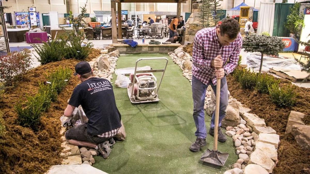Michael Cooley, left, and Alex Lent prepare a putting green for New Image Roofing and Construction’s exhibit for the 2015 Home Show at Century II. The show returns this weekend.