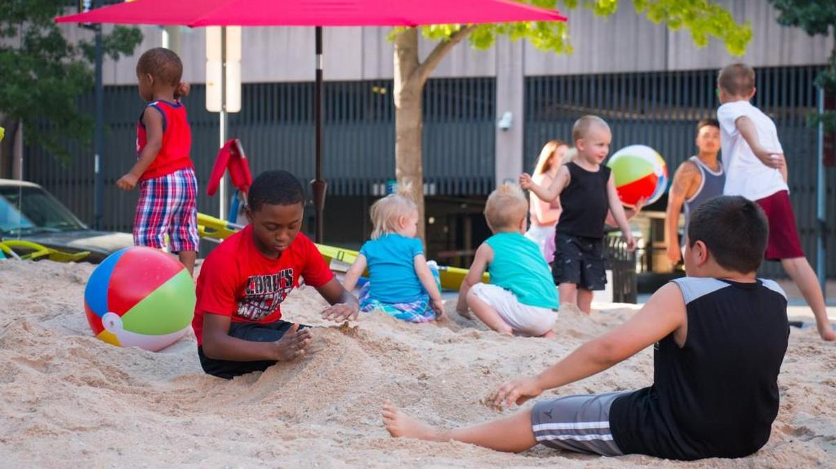 Kids enjoy a makeshift beach at downtown’s ICT Pop-Up Urban Park on Saturday.