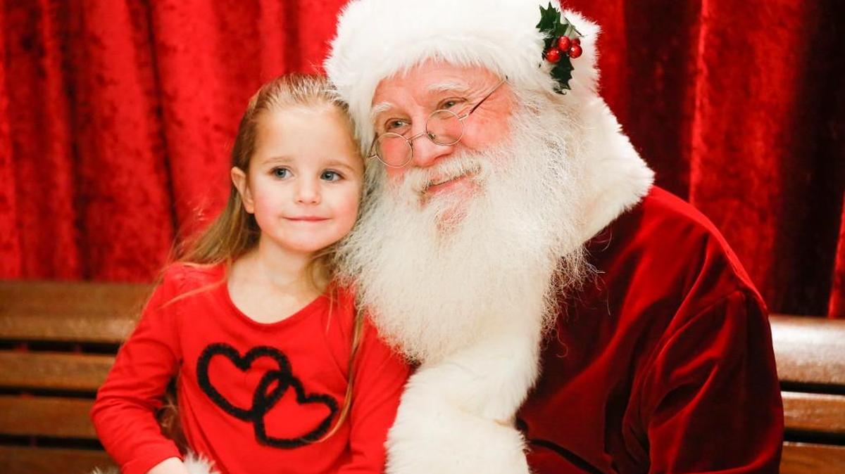 Santa poses for a picture with three-year-old Sophia Wallis inside of Century II during “A Night with Santa,” the city's Christmas celebration, in 2014. The event returns Dec. 8.