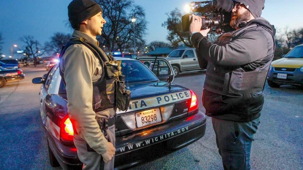 In this file photo from 2014, “Cops” cameraman Bryan Collins, right, interviews Wichita police Officer Vincent Reel before heading out on patrol with him from his Patrol South bureau. The show is filming in Wichita again now.