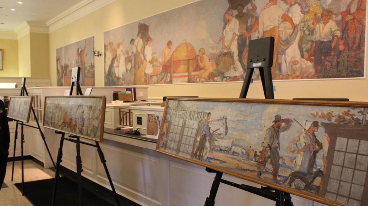 Maquettes for Arthur Covey’s “The Spirit of Kansas” mural at Southwest National Bank on display in front of the finished product, which now hangs behind the teller counter at the bank.