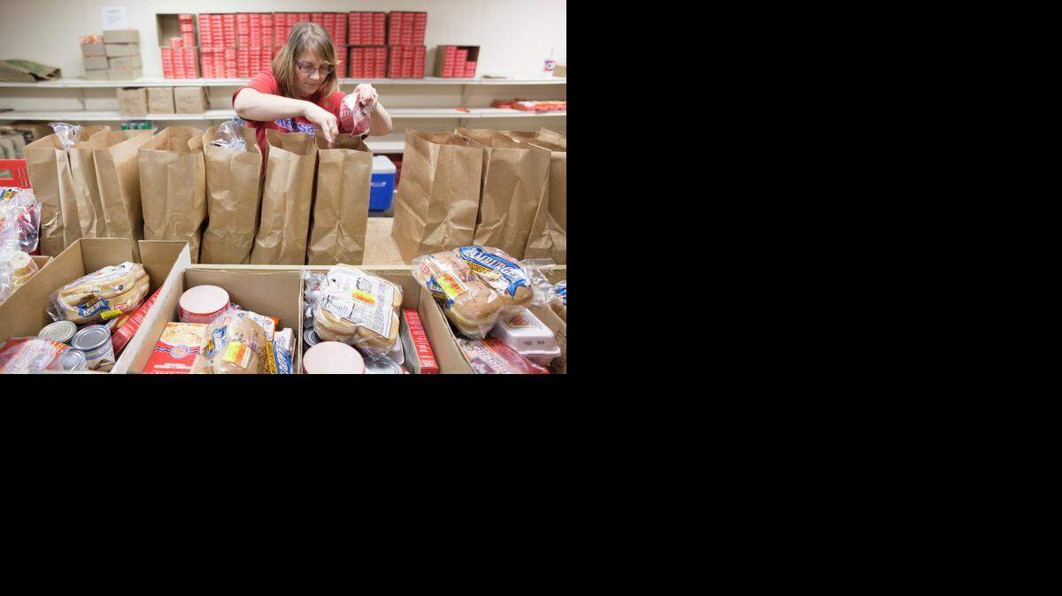 
A volunteer at the United Methodist Open Door food pantry prepares sacks of food at the center.
