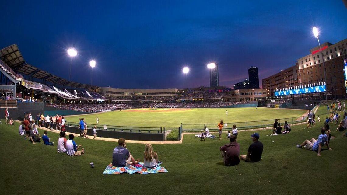 Fans sit on the lawn to watch an OKC Dodgers game at the stadium in Bricktown.