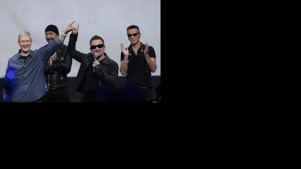 
Apple CEO Tim Cook, left, smiles next to U2 members, The Edge, Bono, and Larry Mullen Jr. during an announcement of new products on Tuesday, Sept. 9, 2014, in Cupertino, Calif. 
