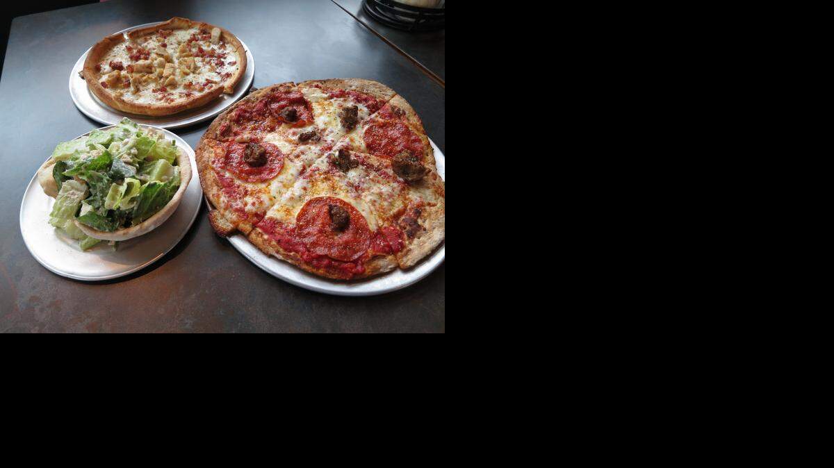 
A selection of dishes from Pie Five include, clockwise from bottom left, a chicken Caesar side salad, a chicken Carbonara pizza on pan crust and a pepperoni and meatball pizza on a whole-grain crust.
