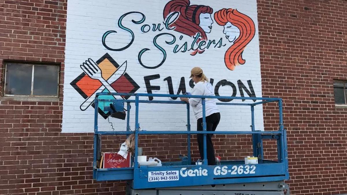 Tanya White paints a mural on the side of the soon-to-open Soul Sisters Fusion, a restaurant at 1812 W. Douglas.
