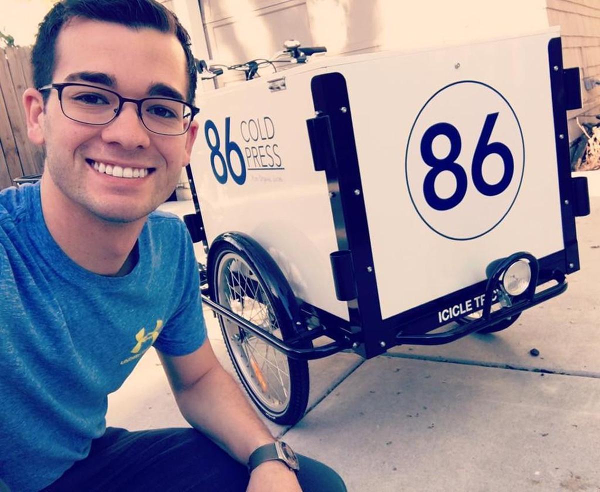 In the early days of 86 Cold Press, Austin Dugan sold his juices from a delivery bike hooked to a cart. This photo is from 2018.