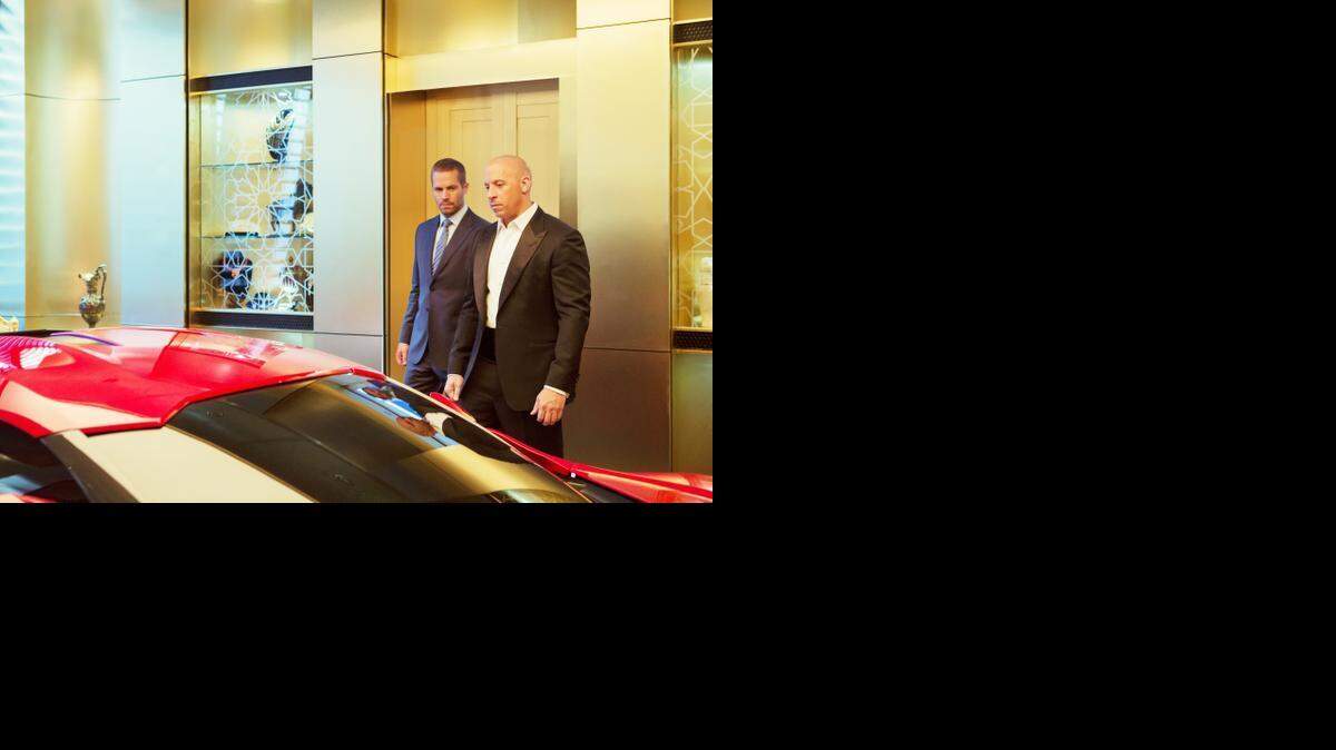 
Brian (Paul Walker, left) and Dom (Vin Diesel) size up an auto in “Furious 7.”
