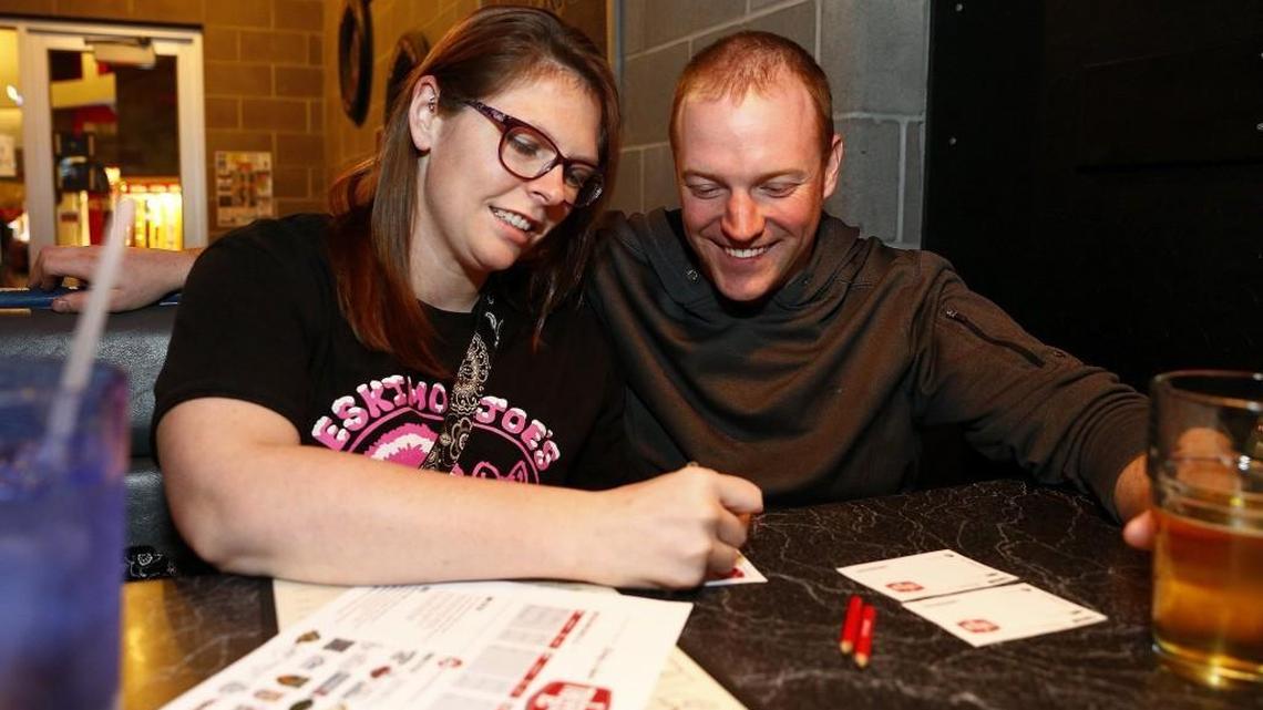 Amanda Wolker, left, and Ty Smith put their heads together to answer a trivia question at AJ’s at the Alley.
