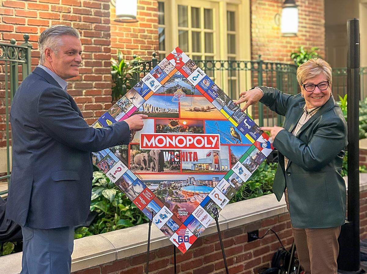 Wichita State University President Richard Muma and President of Wichita State University Campus of Applied Sciences and Technology Sheree Utash point to their WSU-inspired Monopoly squares and artwork during the game's unveiling Wednesday evening.