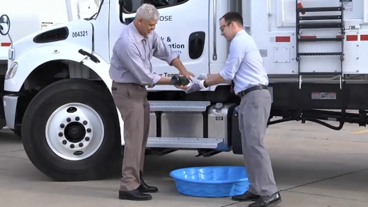 Former Wichita parks director Troy Houtman (left) and former Wichita Mayor Brandon Whipple prepare to smash a bottle of champagne to christen a new trash truck for the Parks Department in this photo from last year.