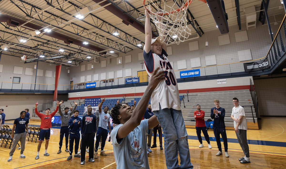 Ryker Ammons, 10, gets help with a dunk from Newman basketball player Terrell Wright after Ryker signed his letter of intent to become an honorary member of the Newman Jets’ basketball team on Thursday. The signing event was organized by Team IMPACT, a national nonprofit that connects children facing serious or chronic illnesses with college athletic teams.