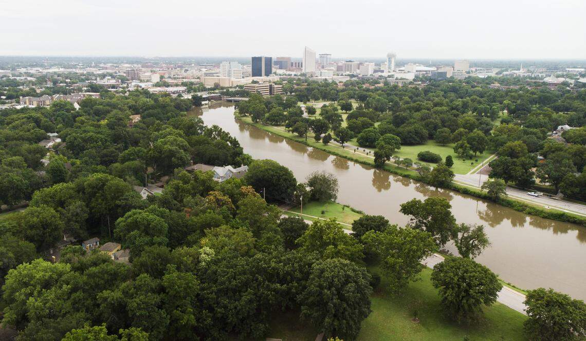 A view of downtown Wichita with Central Riverside Park and the Little Arkansas River in the foreground. A 2018 urban tree canopy assessment by the city found the existing tree canopy removed 3 million tons of air pollution annually, valued at $107 million; absorbs $4.7 million worth of stormwater runoff; and holds $100 million worth of stored carbon.