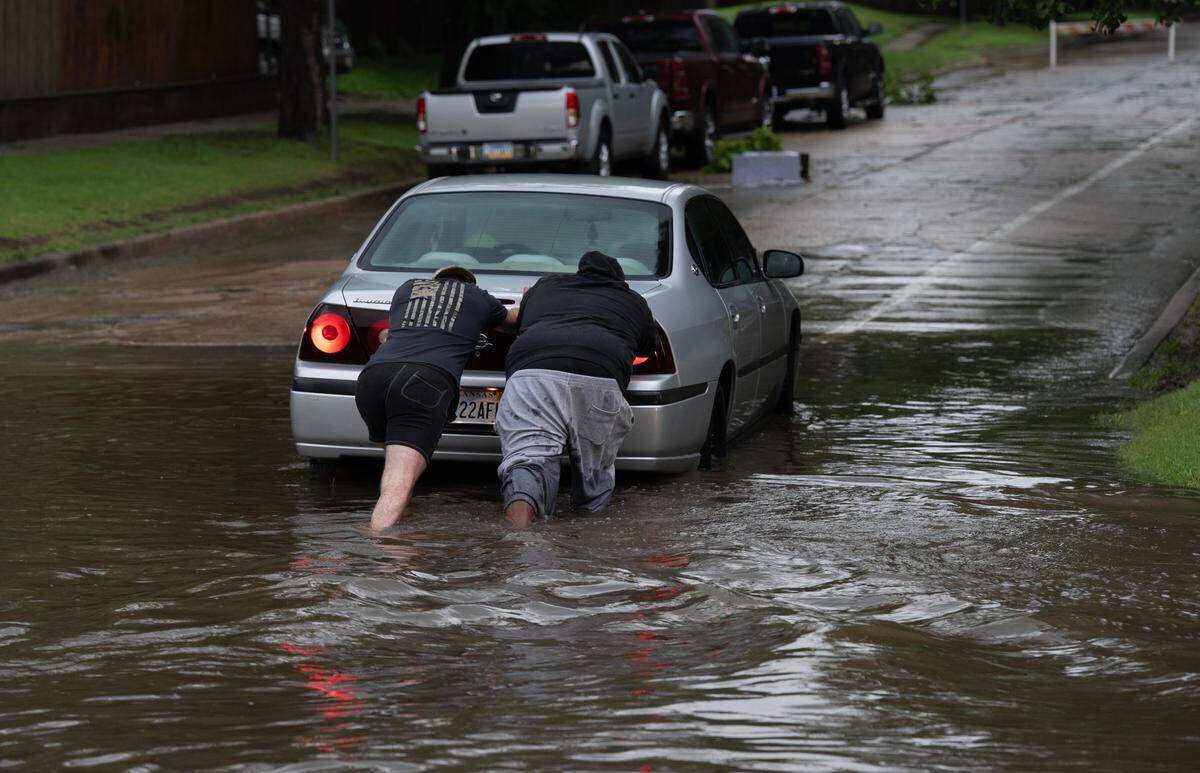 The man on the right helped the driver of this car, on the left, get his car out of the intersection of First and Bleckley. When the car’s driver got out of the car he said, “ Well, it was deeper than I thought.”