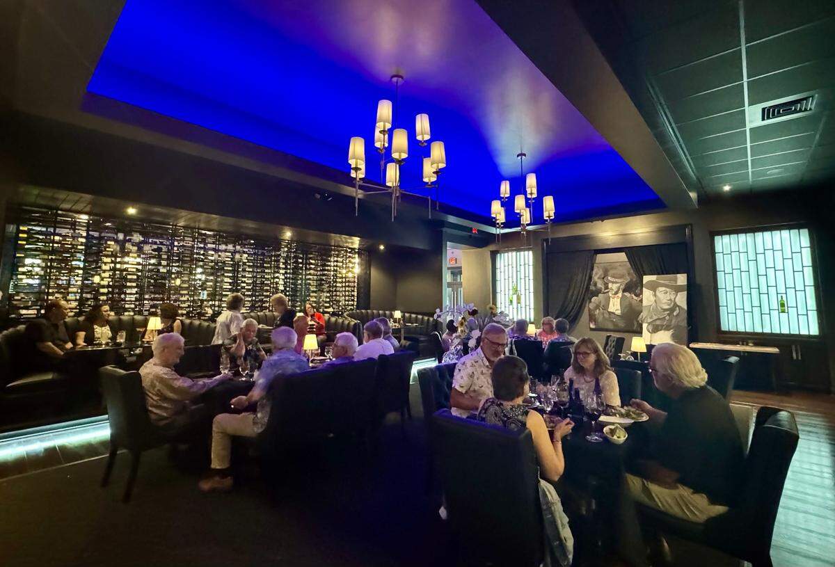 The dining room at KVH Chophouse has dim lighting, half-circle booths and tables and chairs. 