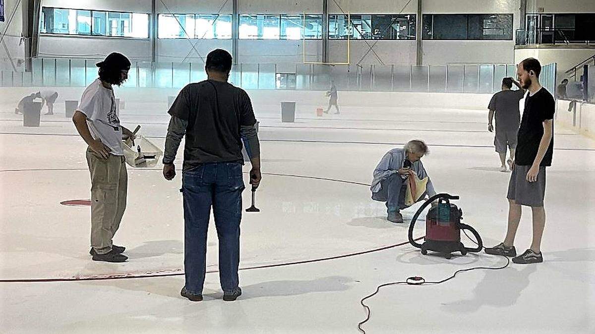 Community volunteers paint new lines on the ice after a meltdown at the Wichita Ice Center.