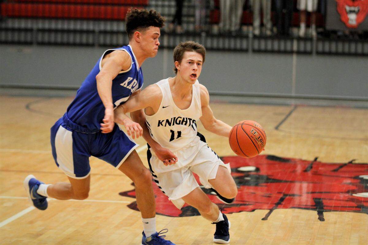 Trinity Academy’s Caden Vanlandingham rounds the corner on Kapaun’s Jarius Kennedy during the Knights’ 68-55 win over the Crusaders in the semifinals of the Bluestem Classic in El Dorado on Friday night. (Jan. 18, 2019)