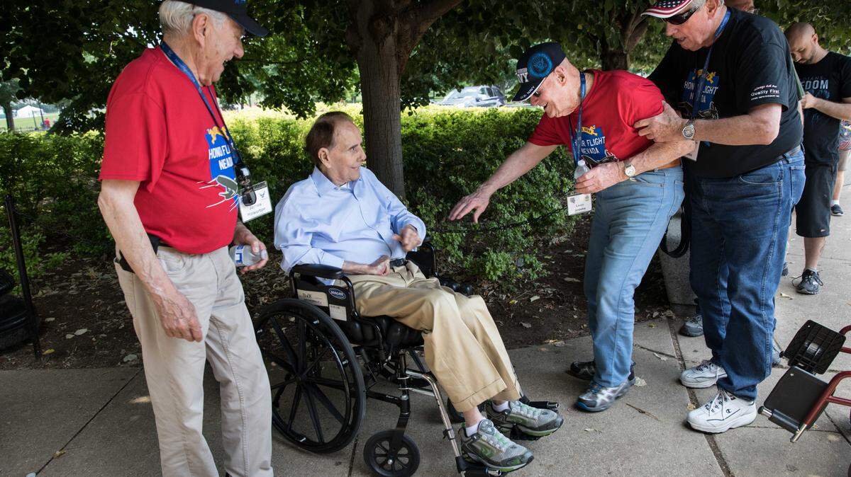Navy veteran Leon Brooks of Nevada, second from right, got out of his wheelchair to greet former Senator Bob Dole, R-Kansas, while Air Force veteran James Howerton, far left, watches, at the National World War II Memorial during an Honor Flight trip to Washington, D.C., on June 9, 2018.