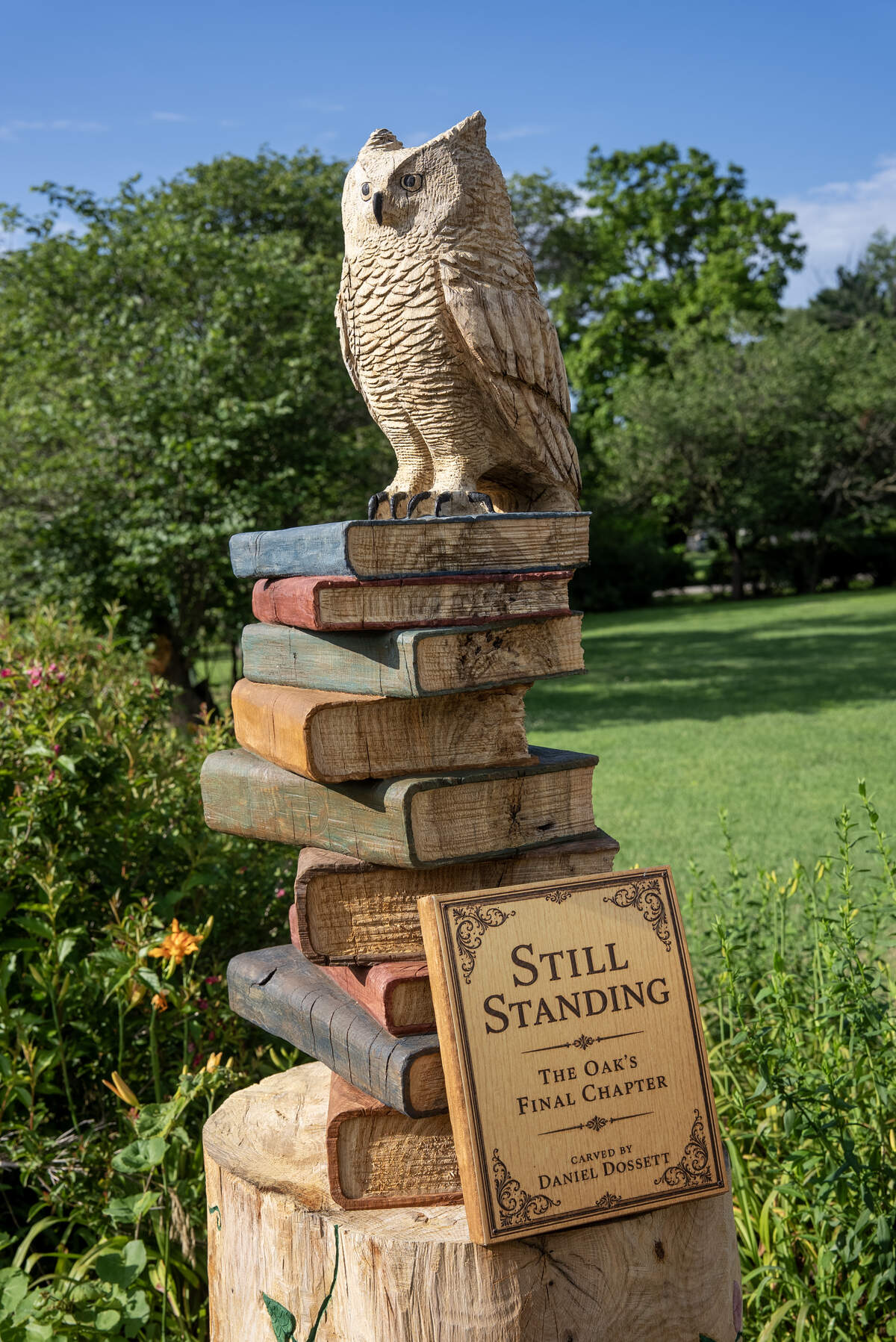 Daniel Dossett turned an Andover oak trunk into lighthouse and owl carvings, discovering a new woodcarving talent and other artistic interests. The owl was inspired by a great horned owl that used to live in the oak tree and the books represent the idea of knowledge, wisdom and education.