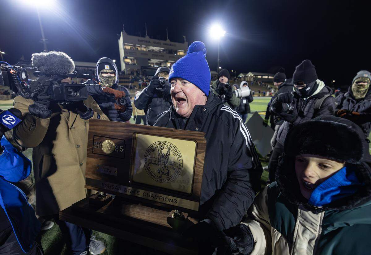 Kapaun head coach carries the state championship trophy on Saturday after leading the Crusaders to the 4A state title. This was Schartz’s first state championship in nearly 40 years of coaching. Kapaun defeated Bishop Miege 56-21.