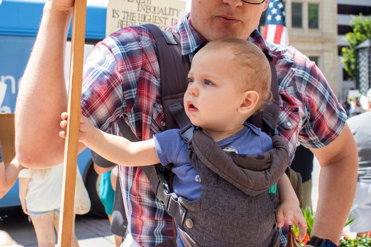 Infant Jonathan reaches for his father, Daniel Mealiff’s, sign on Saturday. It was both of their first protests.