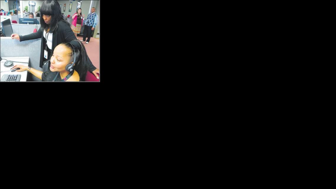 Training supervisor Aurora Mims, left, helps associate Cheree Kelly with a call Monday, the first day that Starwood Hotels began operations at its new contact center at the former Wichita Mall.