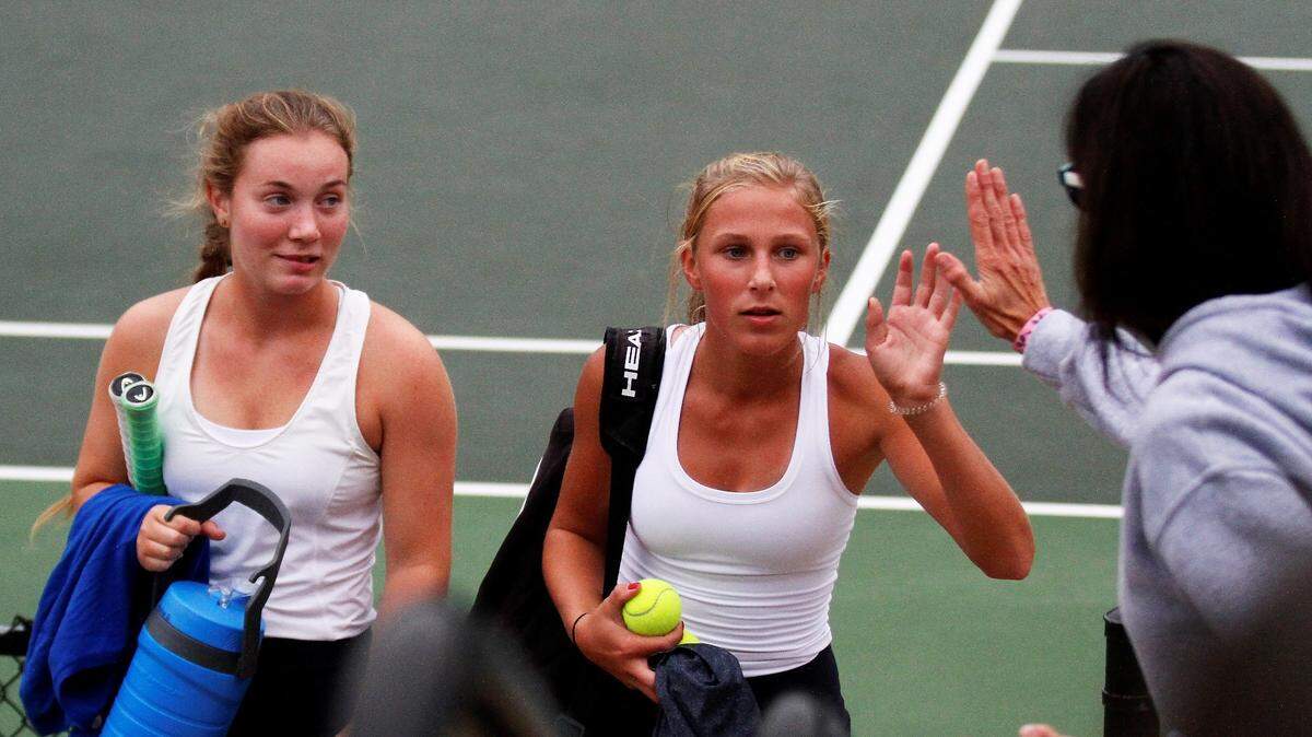 Kapaun senior Eleanor Baldwin (left) and freshman Reagan Boleski (right) celebrate their City League doubles championship Saturday with coach Kathy Schulte.