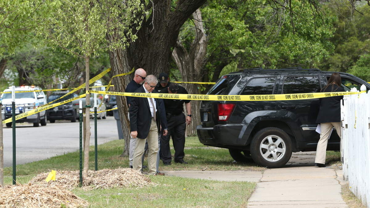 Detectives and officers inspect a black Jeep at the scene of a fatal shooting in northeast Wichita.