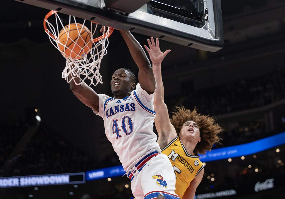 Kansas’ Flory Bidunga throws down an alley-oop dunk over Missouri’s T.O. Barrett during the second half of their game at T-Mobile Center on Sunday, Dec. 7, 2025.
