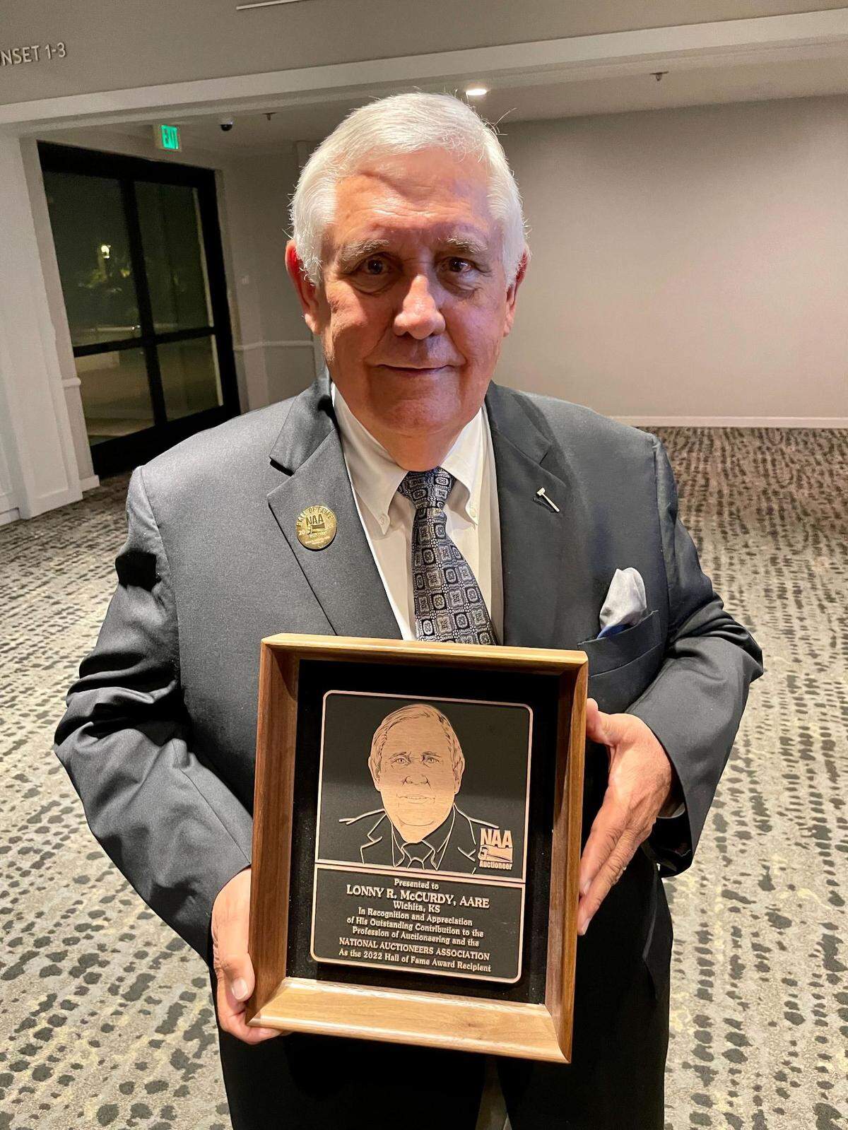 McCurdy Auction founder Lonny McCurdy with the plaque he received after being inducted into the National Auctioneers Association Hall of Fame last month.