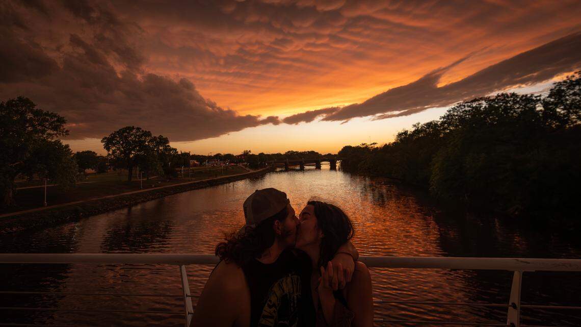 A couple share a kiss underneath a sky of Mammatus clouds near the Keeper of the Plains on Tuesday.
