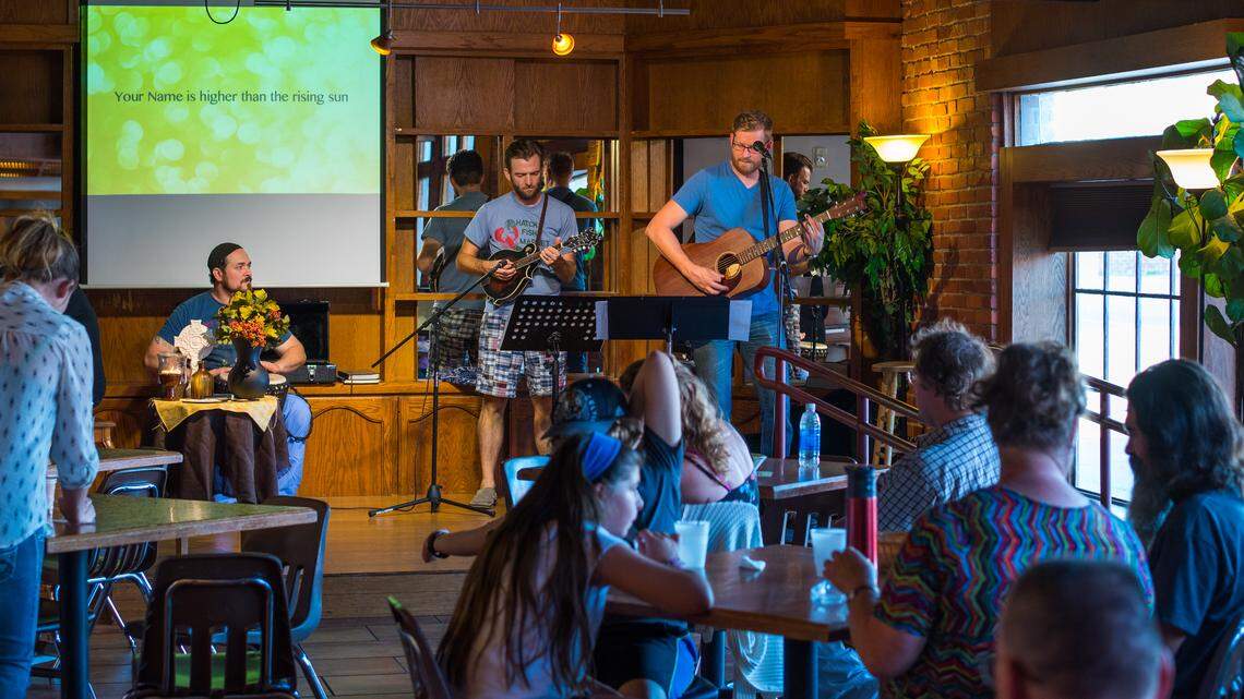 Josh Melcher, music director, plays guitar while Leslie Coates, venue leader, plays mandolin at The Gathering, a church service that meets at Mead's Corner.