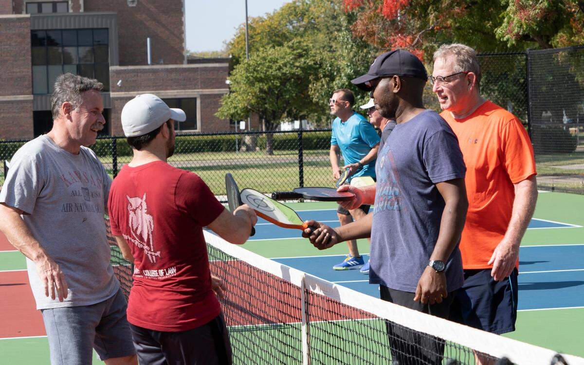 Pickleball players (left to right) Glen Fondaw, Mitch Spencer, Stan Mutuku and Dav Hayner clink paddles after playing a game together on the Seneca Park courts.