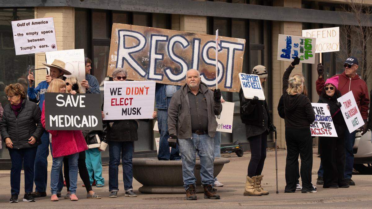 About 200 people protested President Trump, Elon Musk and Rep. Ron Estes Saturday, as Estes spoke to a group of about 35 rallying for tax cuts.