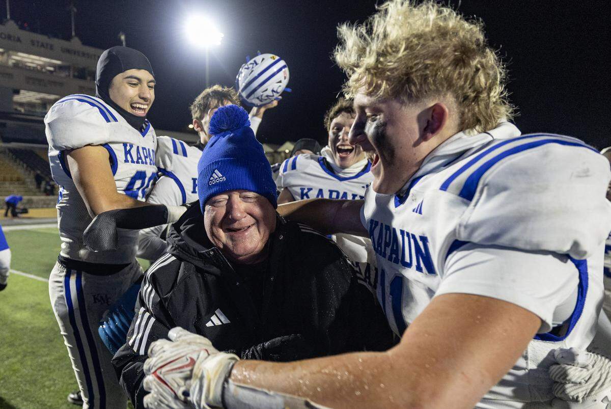 Kapaun head coach Weston Schartz is congratulated by his players on Saturday after leading the Crusaders to the 4A state title. This was Schartz’s first state championship in nearly 40 years of coaching. Kapaun defeated Bishop Miege 56-21.