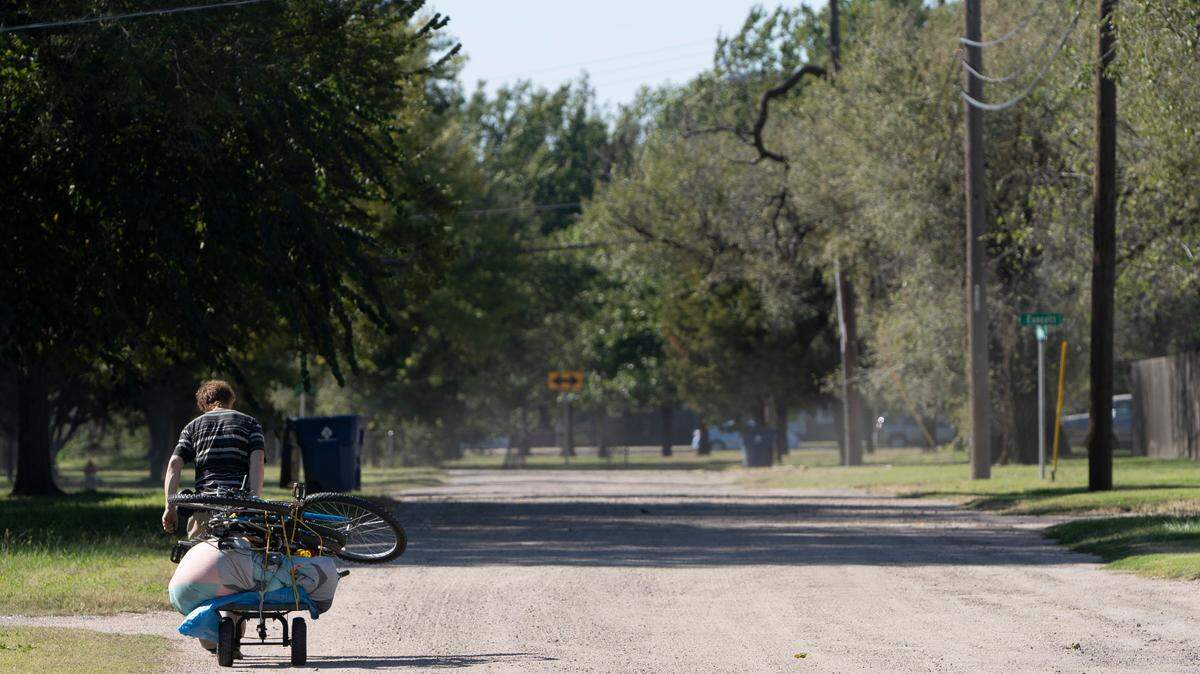 A pedestrian walks down West Munnell Street near Bonn. Wichita Mayor Brandon Whipple and City Council member Jeff Blubaugh want to pave streets south of Kellogg. (October 19, 2021)