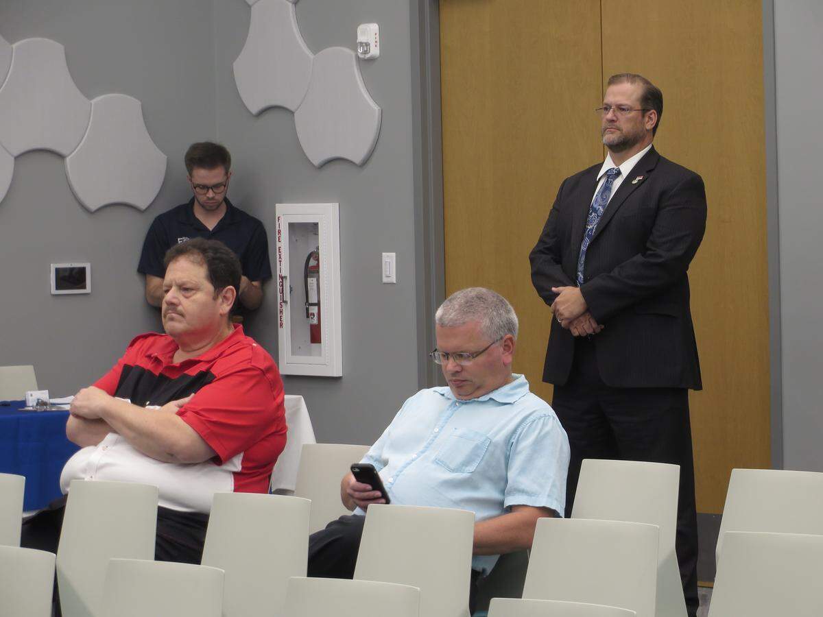 Democratic congressional candidate  James Thompson, right, stands in the back of the room at opponent Ron Estes’ Town Hall, waiting to challenge Estes to debate him in all 17 counties of the 4th District.