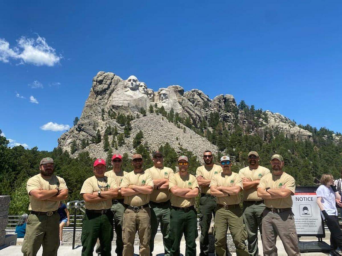 A Kansas squad stands in front of Mt. Rushmore after fighting fires in South Dakota. From left to right: Christopher Hanson, Kansas Forest Service module leader, Chris Hanson Sr., squad boss, Bailey Penner, firefighter, Matthew Miller, faller, Phil Lierz, firefighter, Josh Ward, firefighter, Chris Talmadge, firefighter, Austin Gilliam, faller, Bryce Haverkamp, asst. module leader, and Aaron Kirby, squad boss.