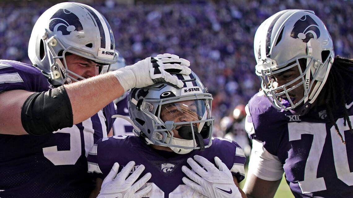 Kansas State running back Deuce Vaughn, center, celebrates with offensive linemen Cooper Beebe (50) and KT Leveston (70) after scoring a touchdown during the first half of an NCAA college football game against Oklahoma State Saturday, Oct. 29, 2022, in Manhattan, Kan. (AP Photo/Charlie Riedel)