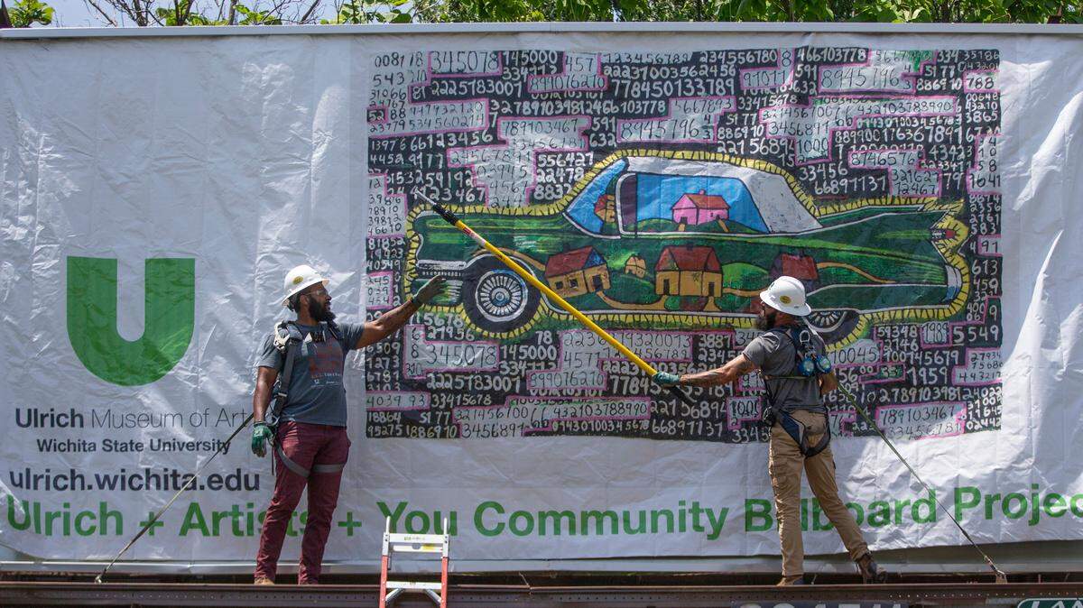 Workers hang a billboard on West 29th Street showing some of the artwork in the Wichita State University’s Ulrich Museum of Art collection.
