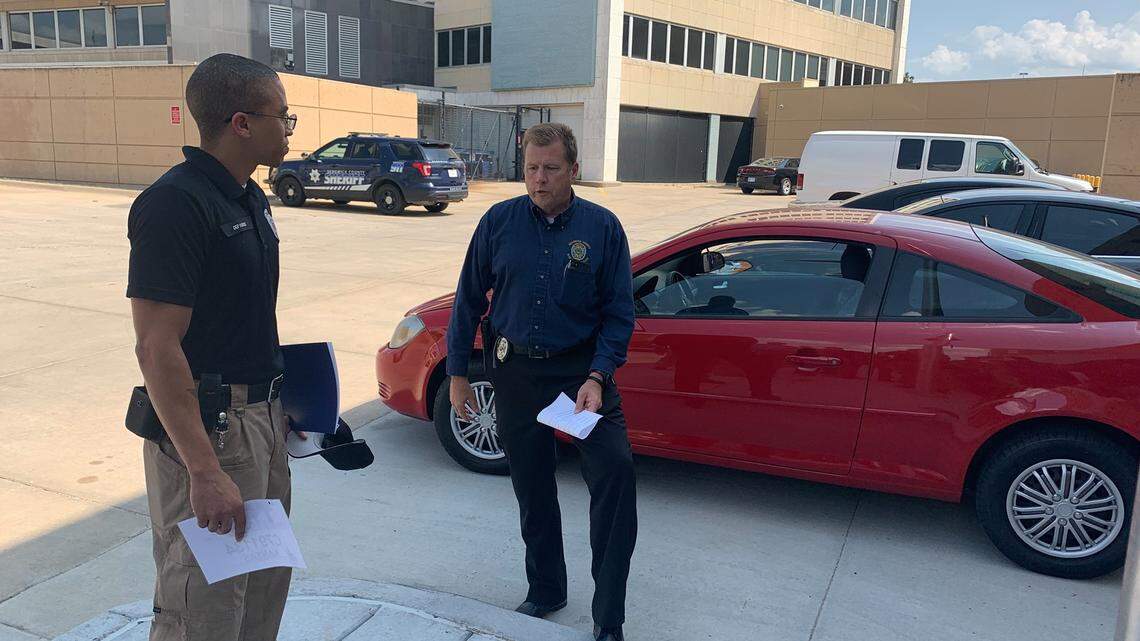Sedgwick County Jail Deputy Caleb Harris, left, is given a red car by colleagues who found out he was riding a bicycle to work.