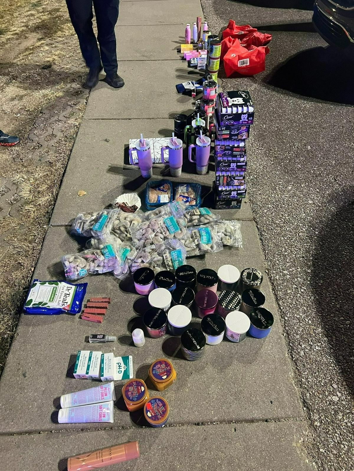 Police officers sort through recovered stolen merchandise in the parking lot of a shopping center.