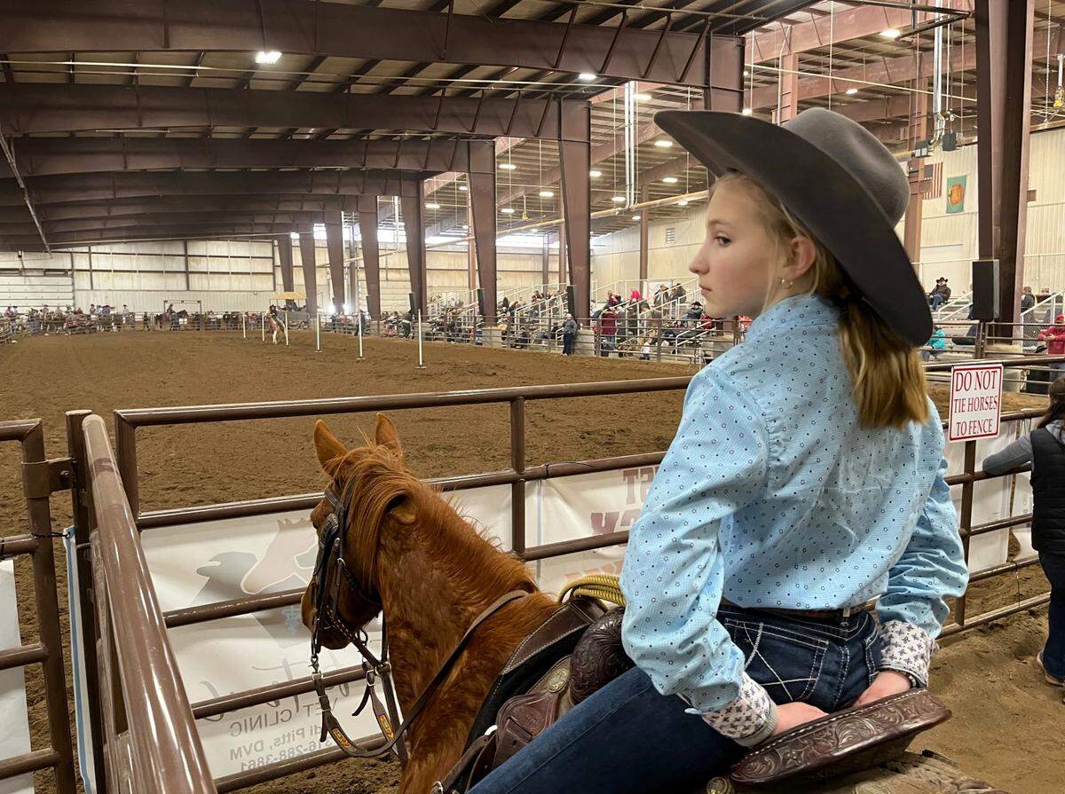 Young Guns competitors wait their turn outside the arena gate during the pole bending event, a timed race that has riders weaving back and forth between the line of white poles.