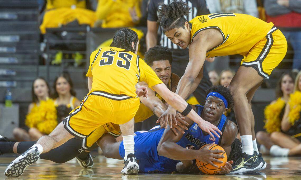 Memphis’ Malcolm Dandridge tries to get control of a loose ball against Wichita State defenders Bijan Cortes, left, Ronnie DeGray III, middle and Kenny Pohto, right, during the first half on Sunday at Koch Arena.