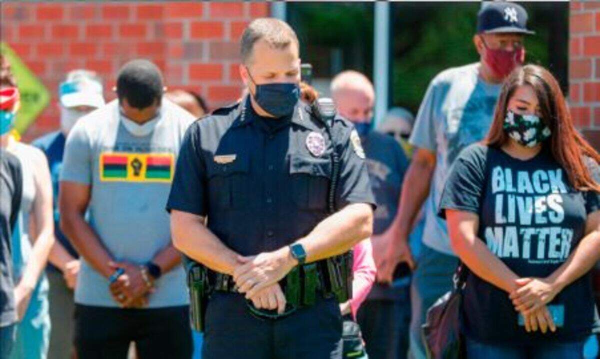 The real photo of Sarah Lopez and Wichita Police Chief Gordon Ramsay praying at a peaceful demonstration over the police killing of George Floyd. Kansas Republicans have misused this picture multiple times.